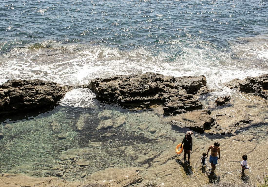 Aerial view of a family with two children walking along a rocky Spanish shore